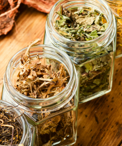 Detail sušených bylín v sklenených nádobách, znázorňujúci prírodné ingrediencie používané vo fytoterapii a bylinnej medicíne.