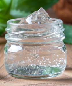 Sklenená nádoba naplnená aloe vera gélom. Aloe vera má protizápalové a upokojujúce vlastnosti, ktoré môžu pomôcť pri liečbe kožných infekcií spôsobených premnožením Candidy.
