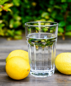 Pohár vody s citrónmi, ideálny na podporu hydratácie a doplnenie vitamínu C, ktorý prispieva k detoxikácii a udržaniu rovnováhy pH tela.